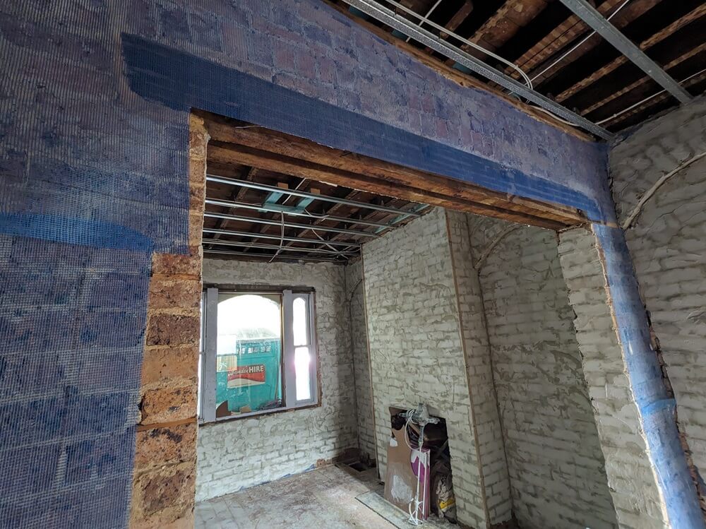 blue mesh protecting 100 year old convict bricks, layered with a first coat of acrylic render